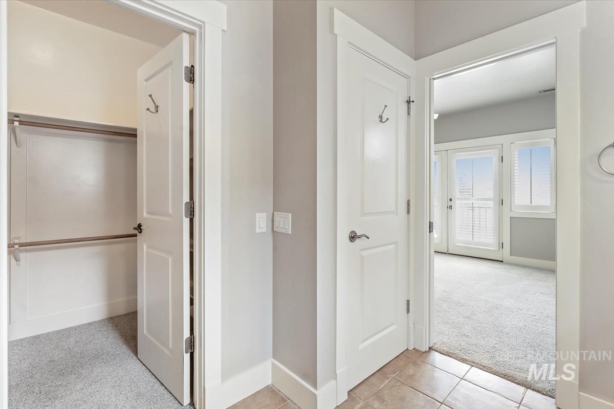 Hallway with light carpet and light tile patterned floors