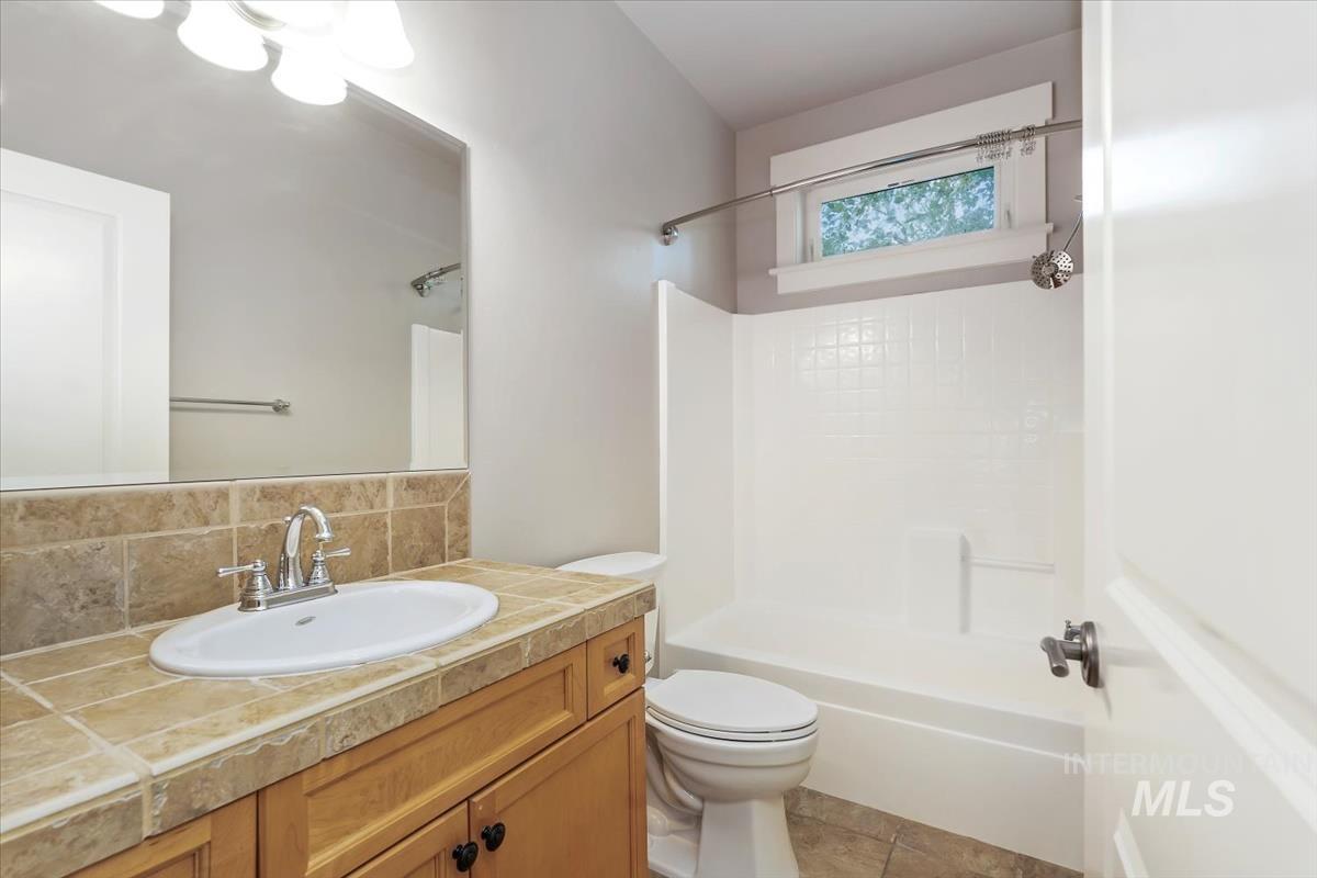 Full bathroom with vanity, shower / washtub combination, decorative backsplash, and light tile patterned flooring