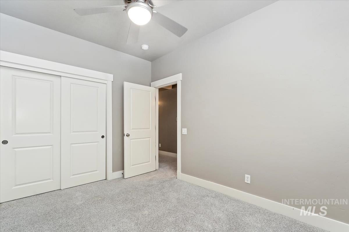 Unfurnished bedroom featuring light colored carpet, a closet, and a ceiling fan