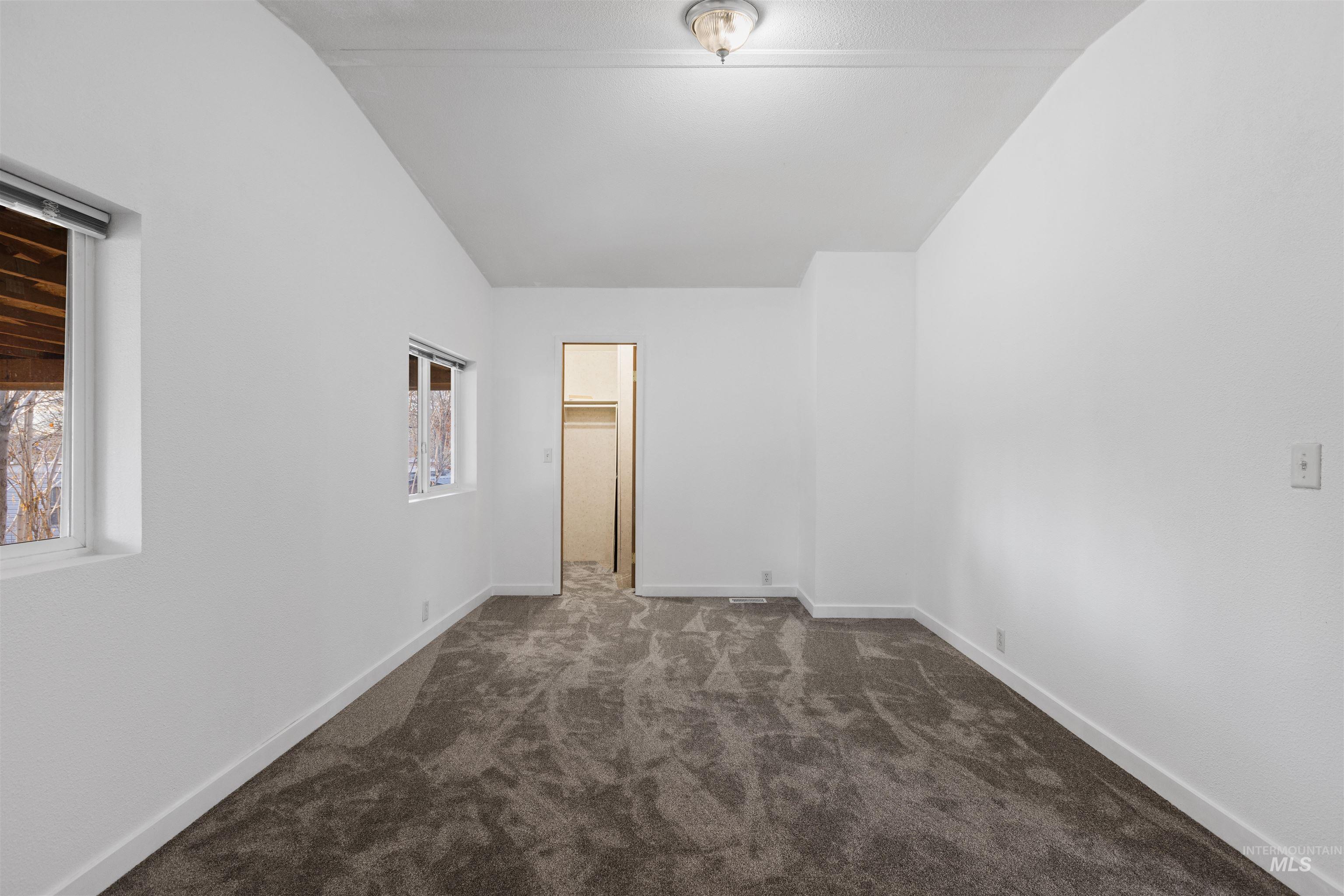 Empty room featuring dark colored carpet and baseboards