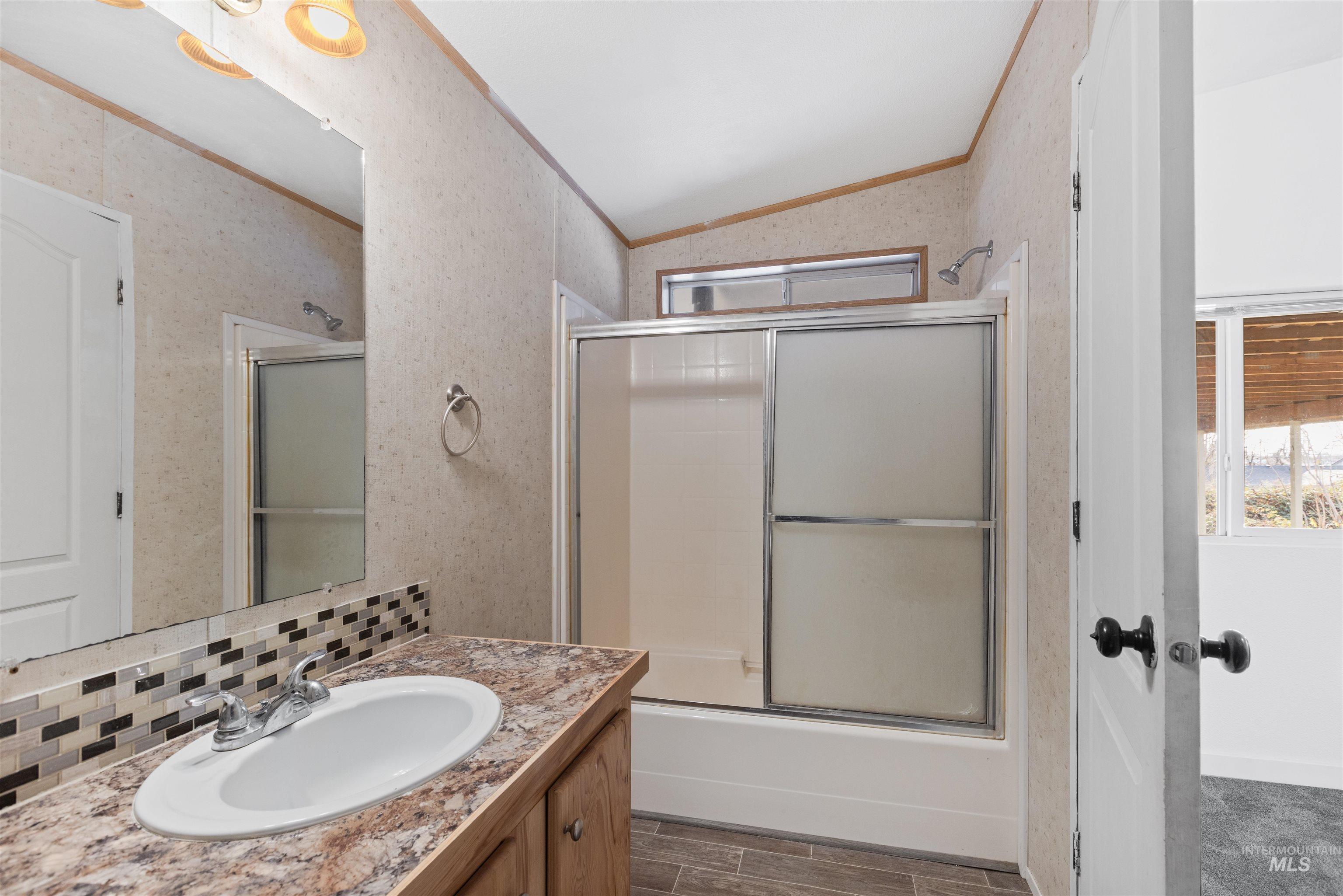 Bathroom with vanity, crown molding, shower / bath combination with glass door, wood tiled floors, and vaulted ceiling
