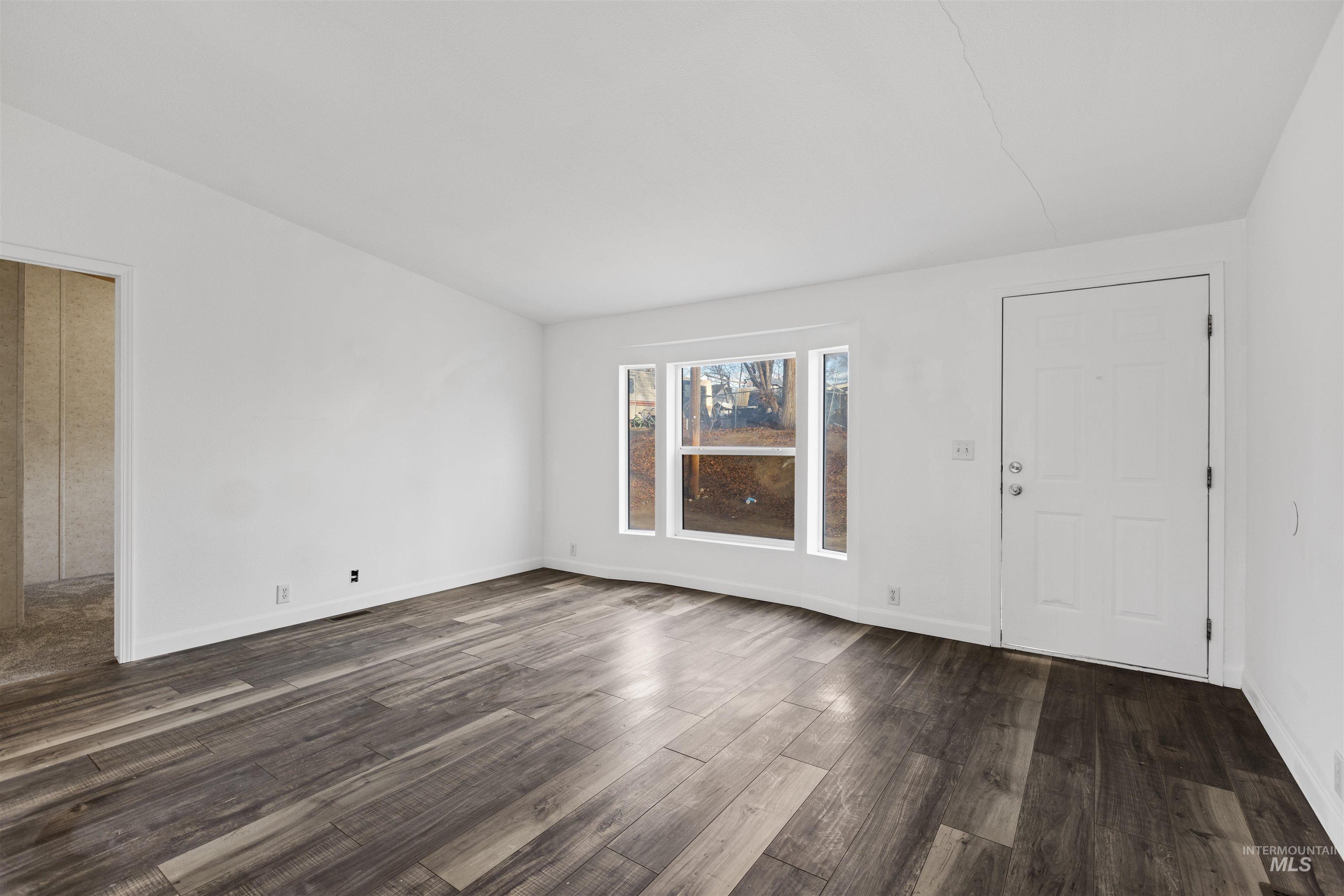 Spare room with dark wood-style floors and baseboards