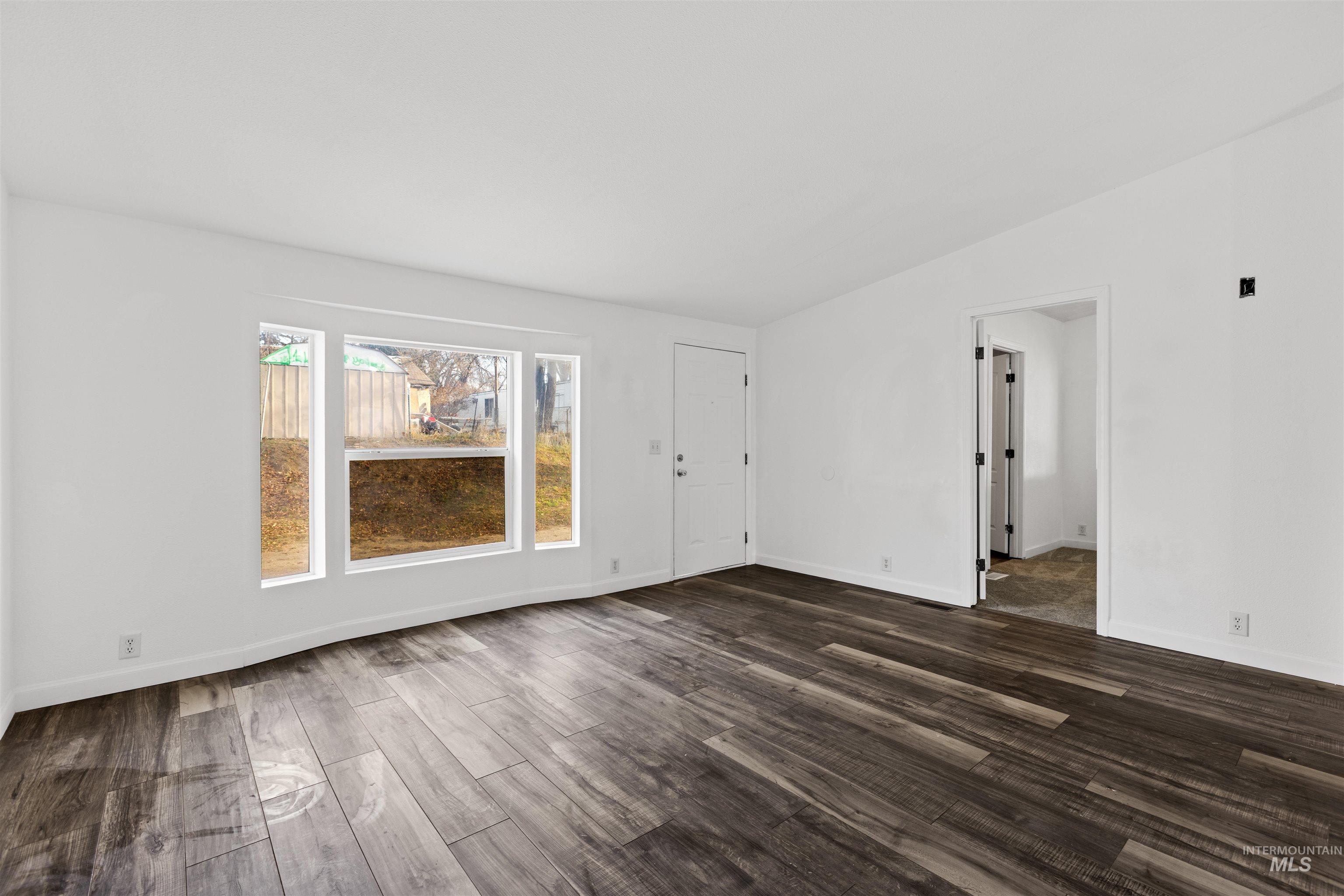 Unfurnished room with dark wood-type flooring and baseboards
