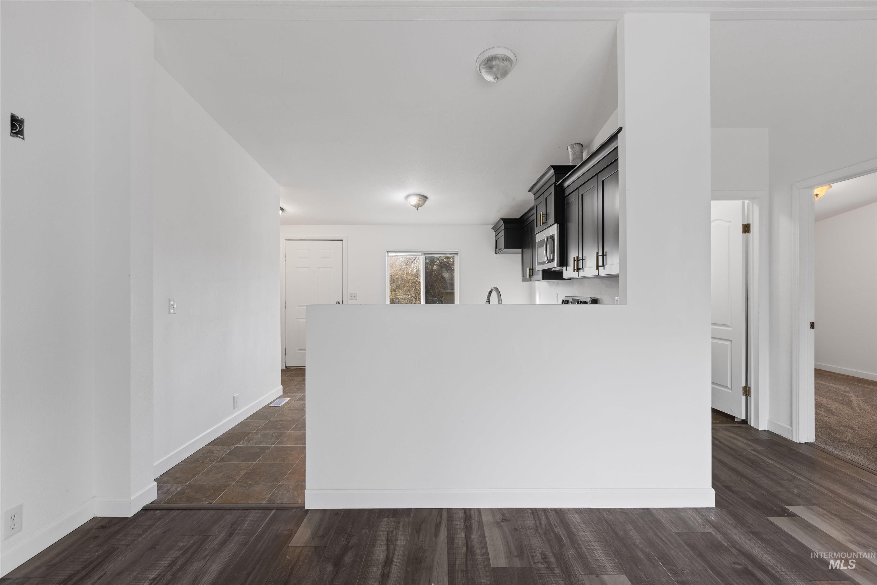 Kitchen featuring light countertops, dark wood-style floors, dark cabinetry, and a peninsula