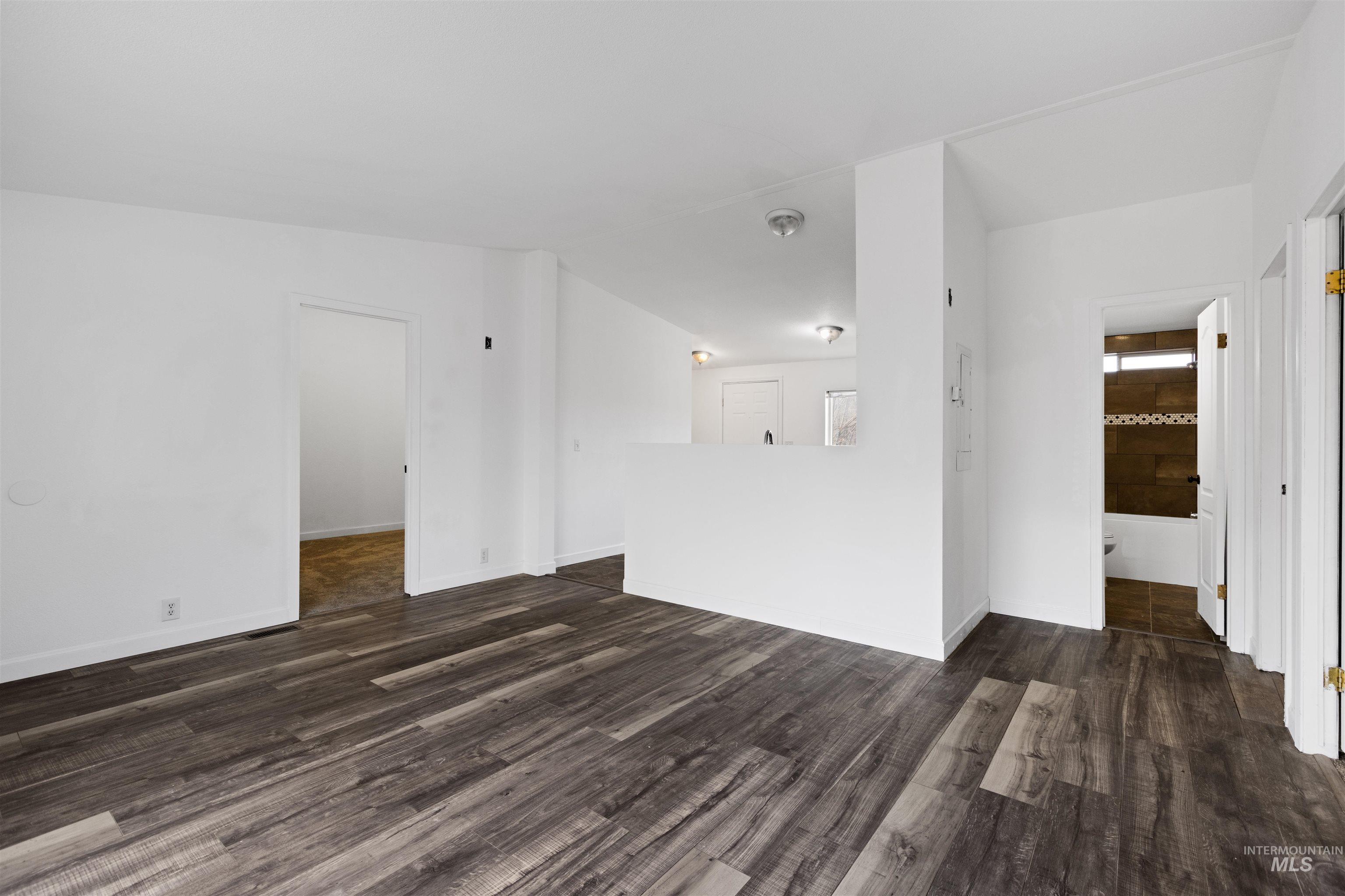 Unfurnished room featuring dark wood-type flooring and baseboards