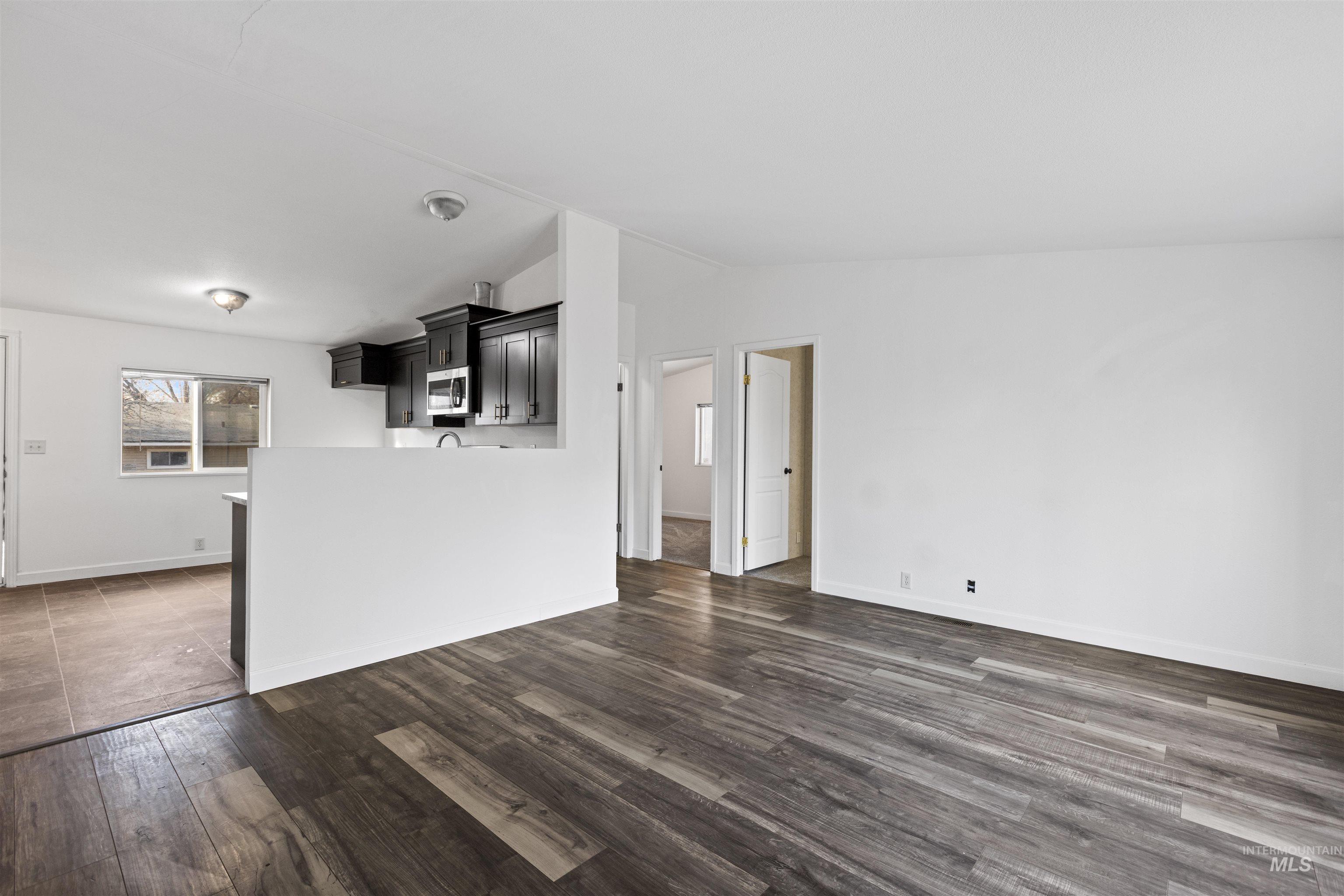 Unfurnished living room with dark wood finished floors and lofted ceiling