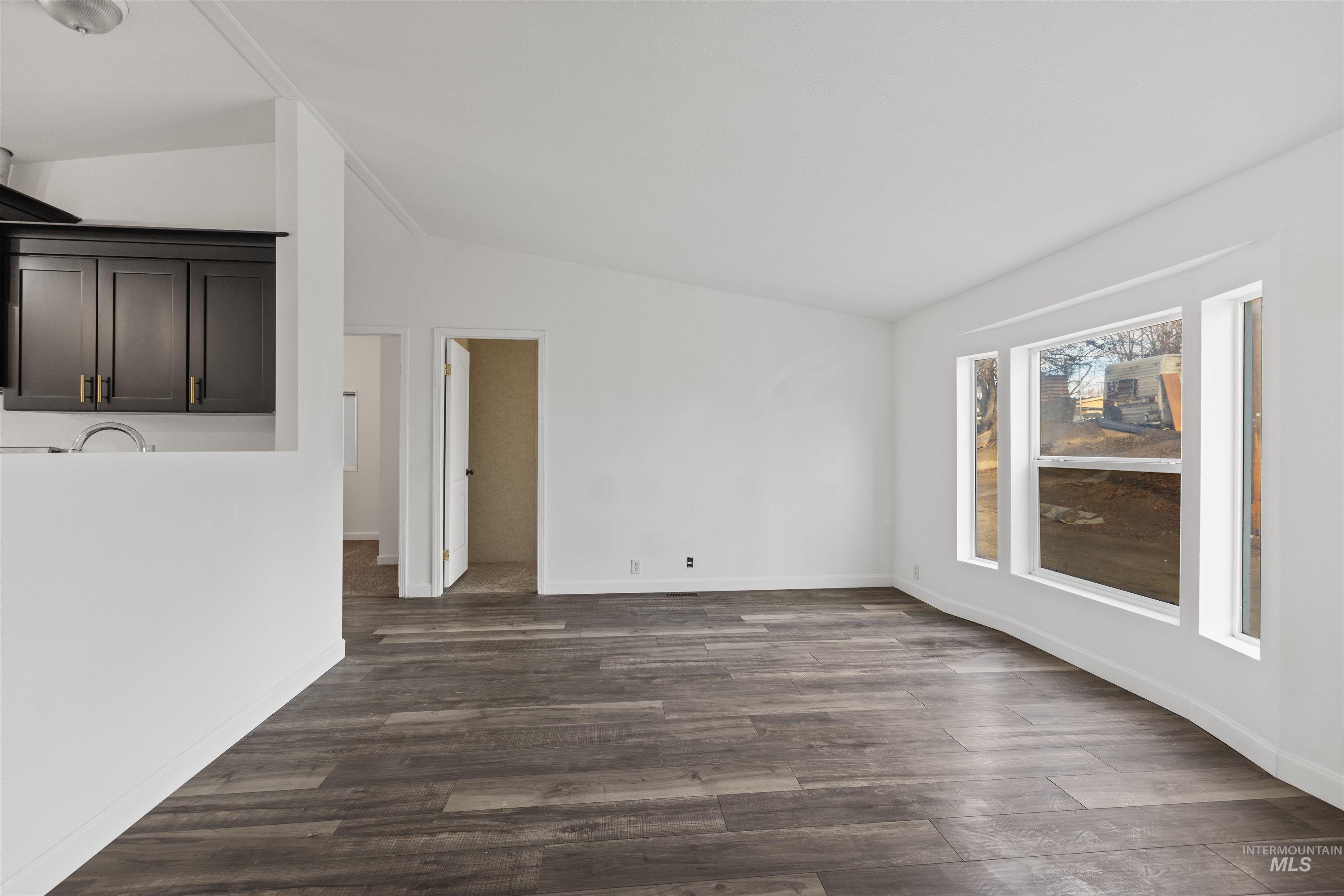 Unfurnished living room with dark wood-style flooring and lofted ceiling