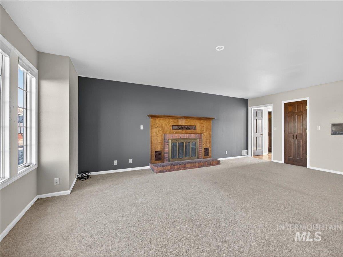 Unfurnished living room featuring a fireplace and carpet floors