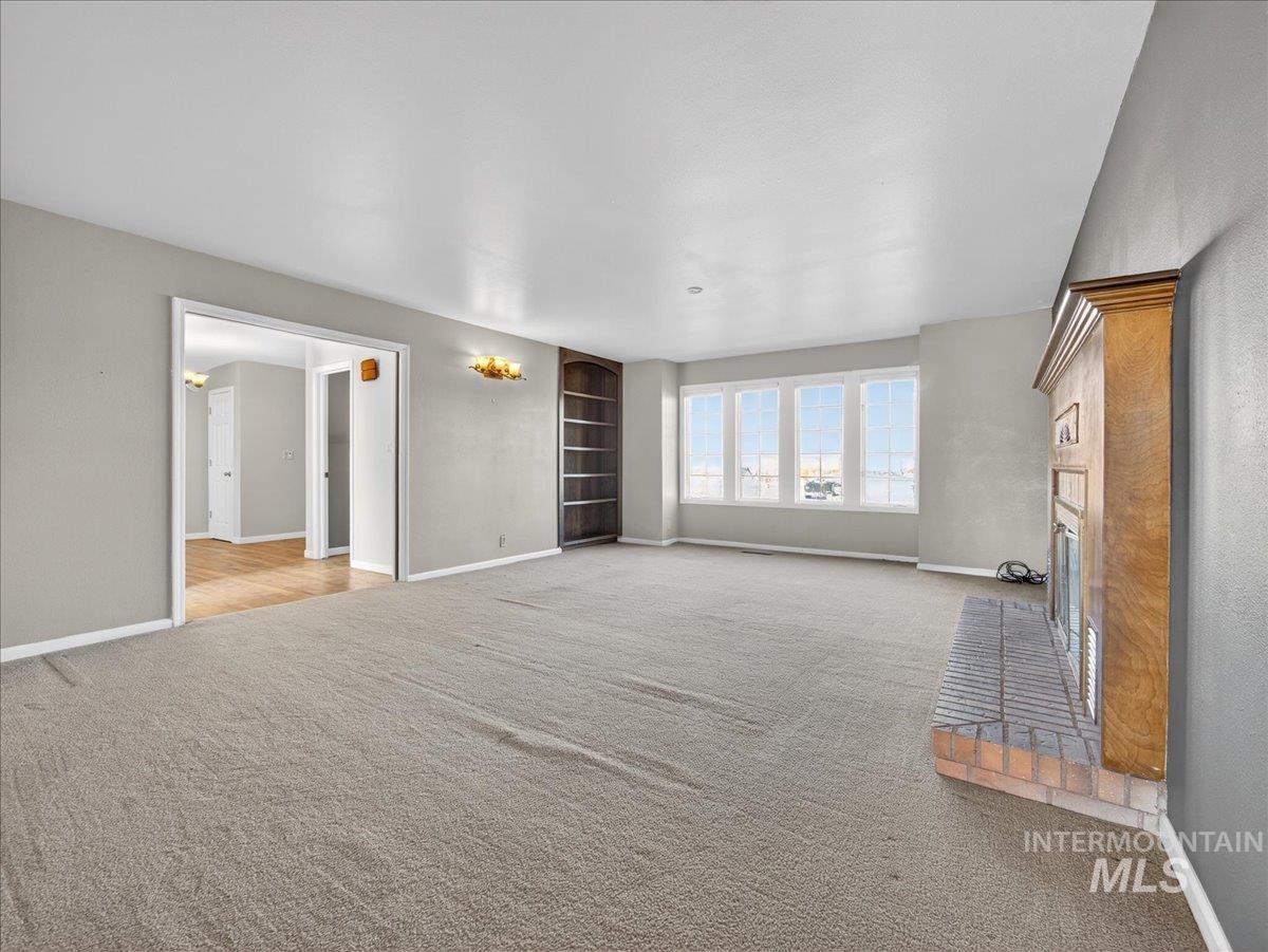 Unfurnished living room featuring a fireplace, light carpet, and built in features