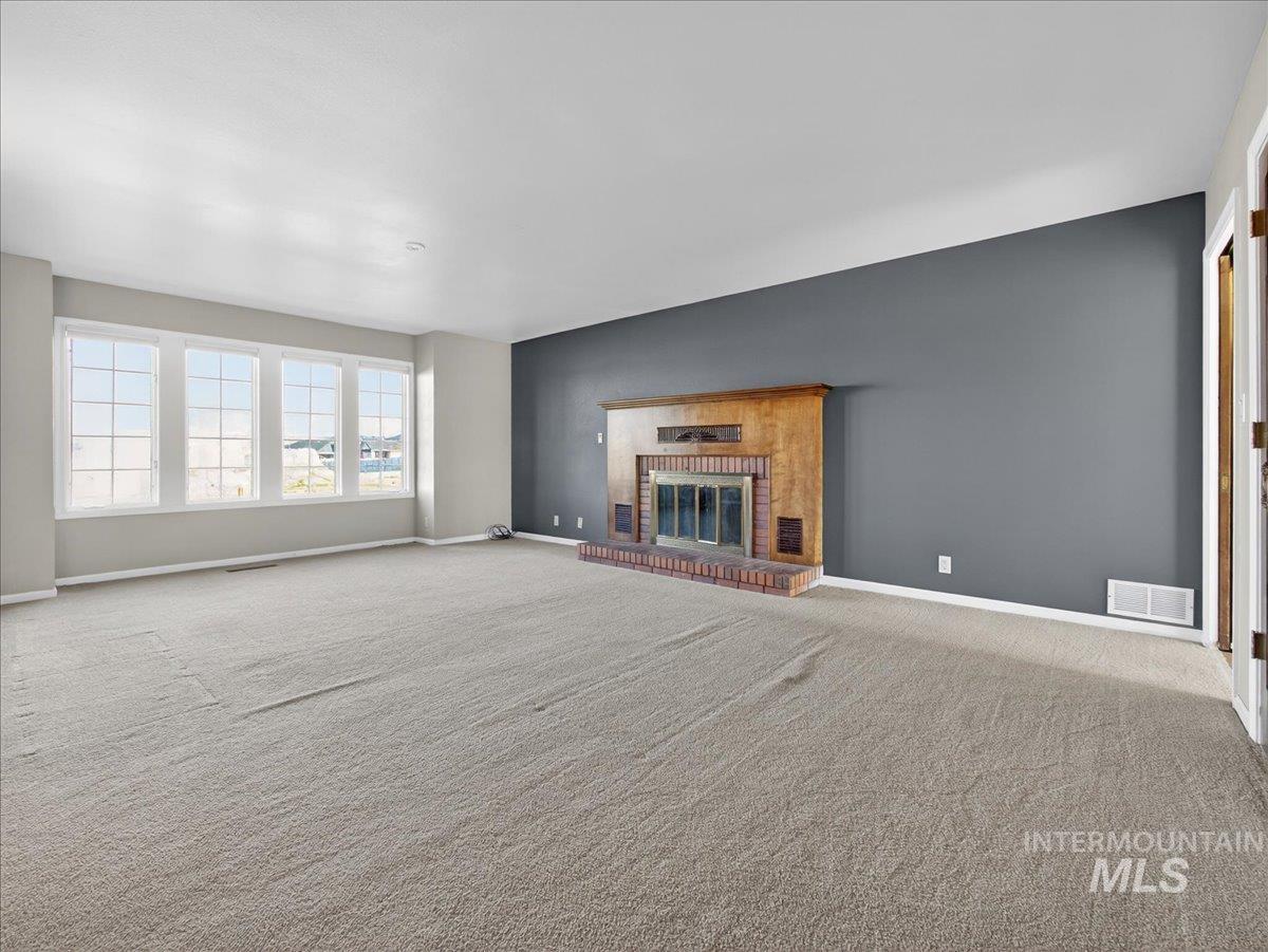 Unfurnished living room with a fireplace and carpet flooring
