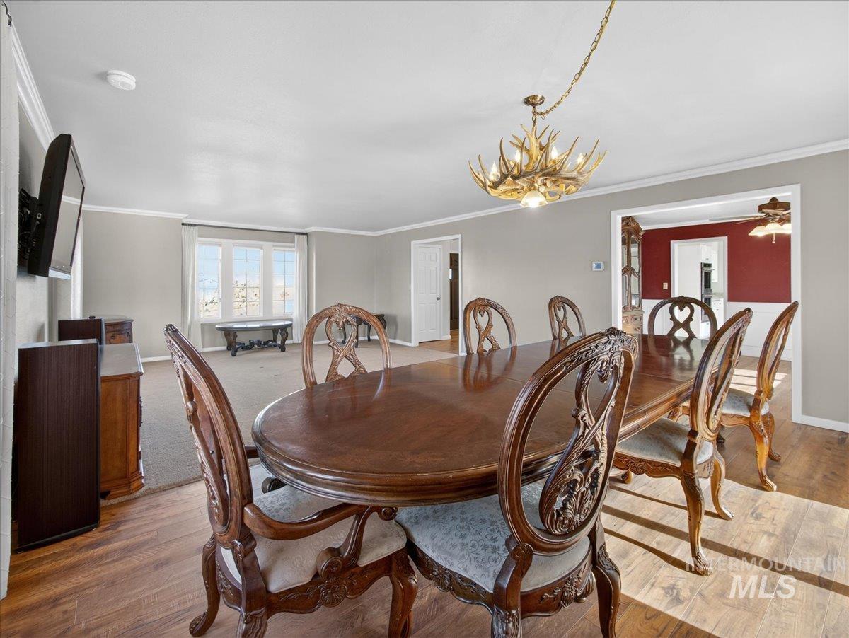 Dining room with wood finished floors, ornamental molding, and a chandelier