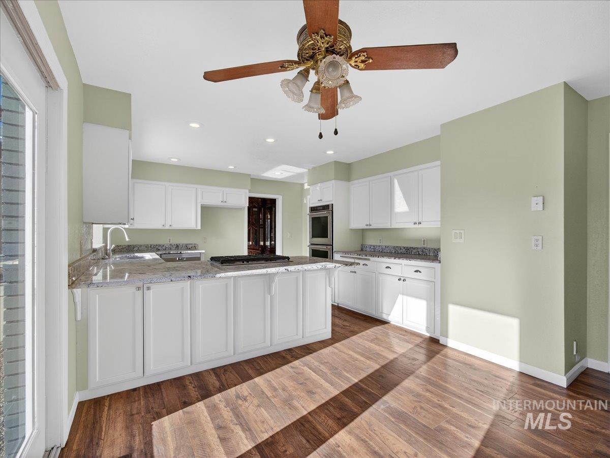 Kitchen featuring white cabinetry, a peninsula, light stone countertops, a ceiling fan, and recessed lighting