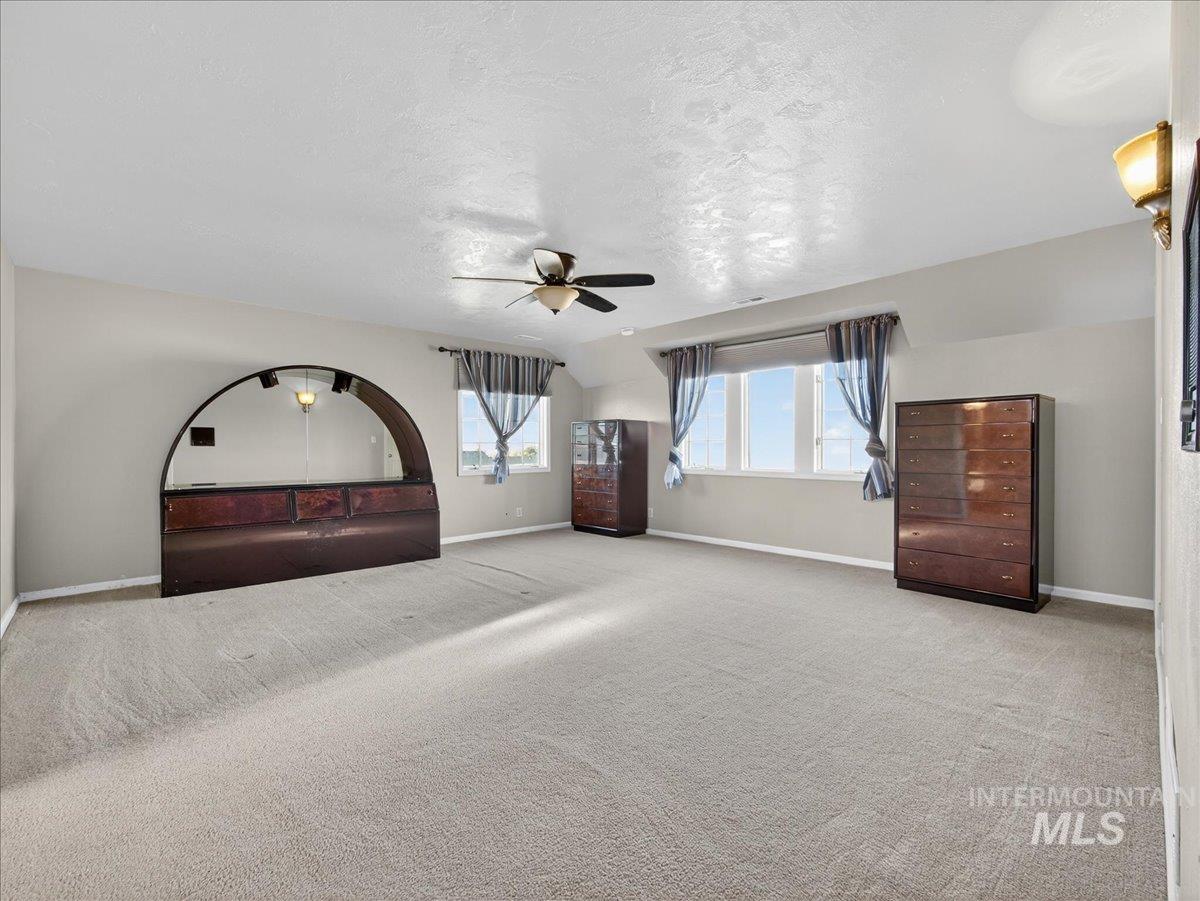 Unfurnished bedroom with ceiling fan, carpet, and a textured ceiling