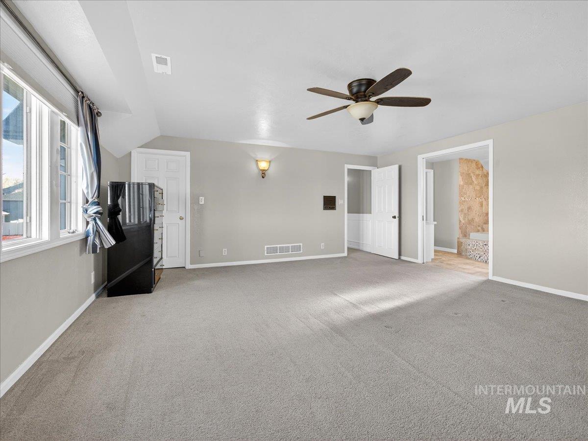 Unfurnished living room with light carpet and a ceiling fan