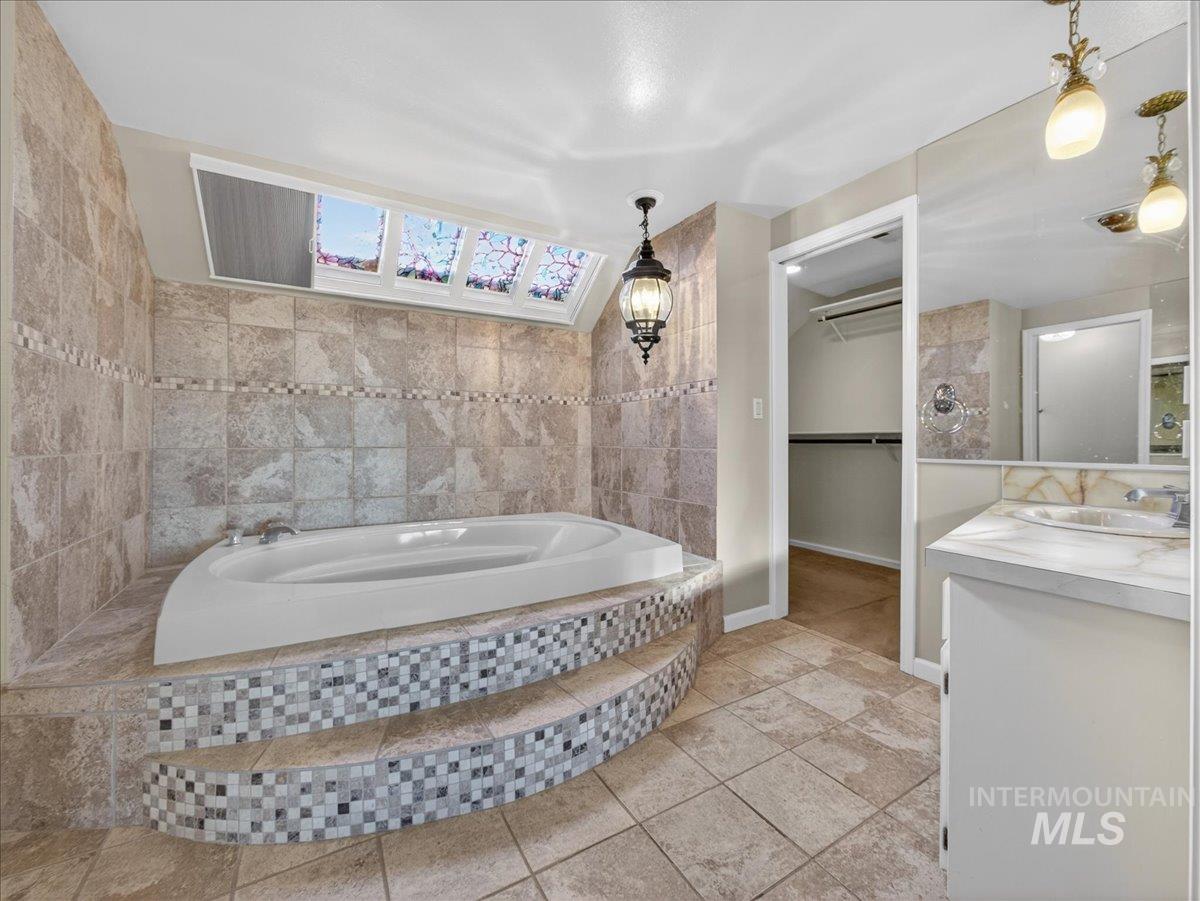 Full bathroom featuring a spacious closet, vanity, and a garden tub