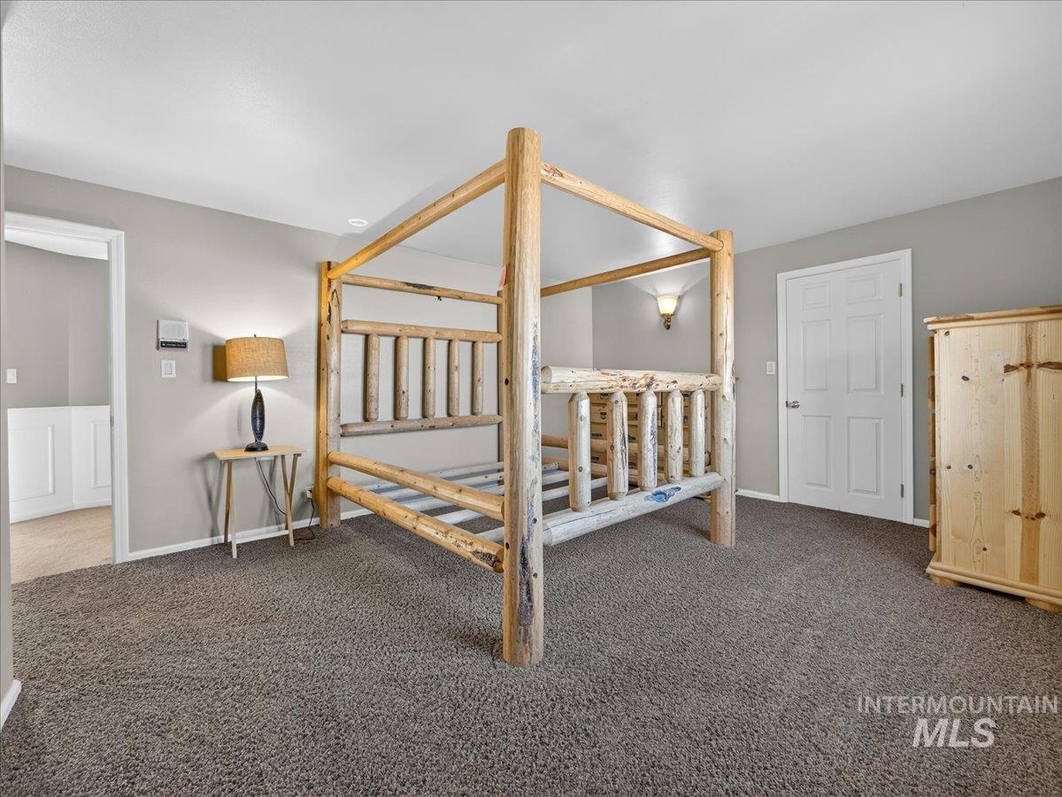 Bedroom featuring dark colored carpet and baseboards