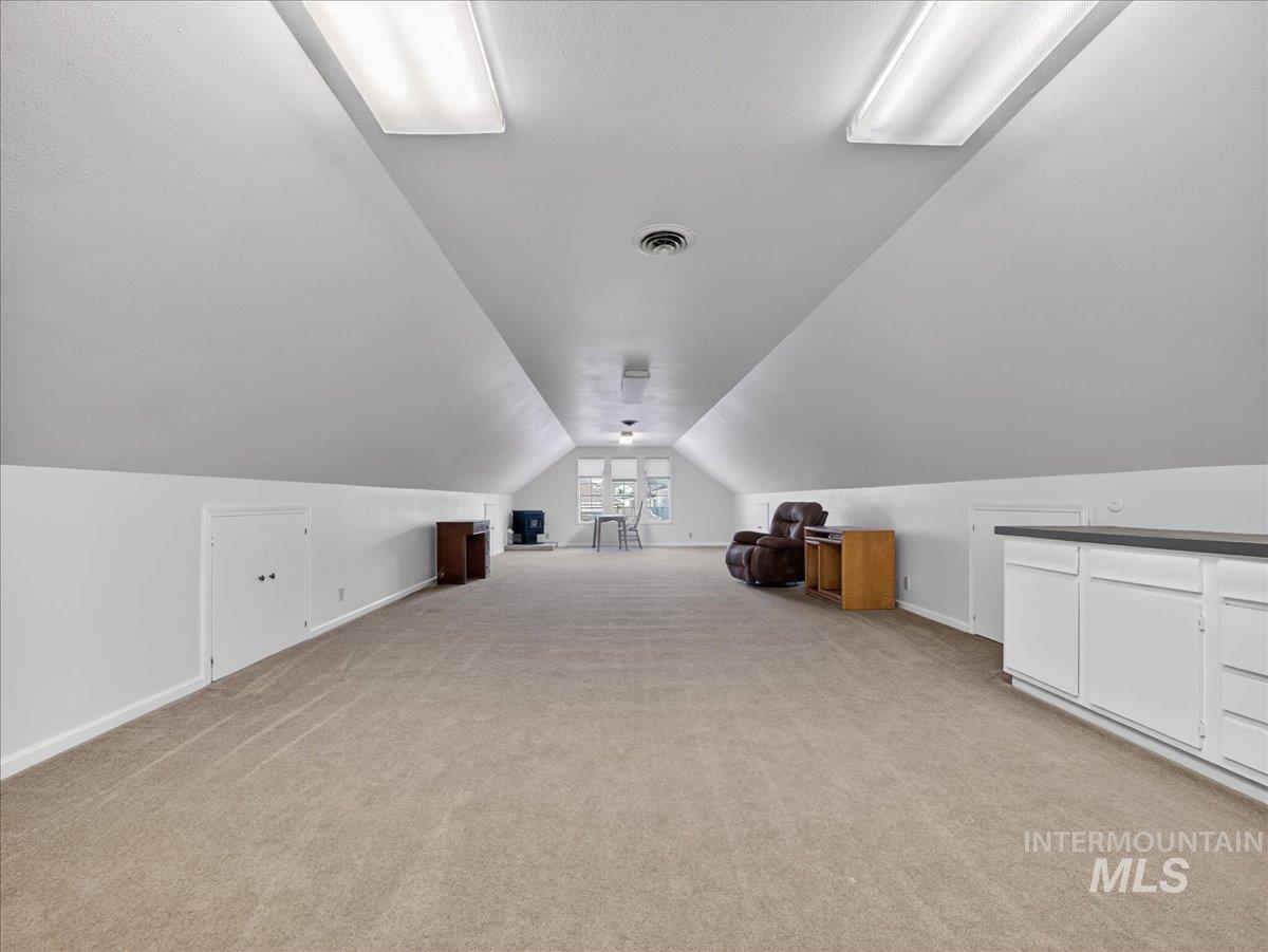 Additional living space featuring lofted ceiling and light colored carpet