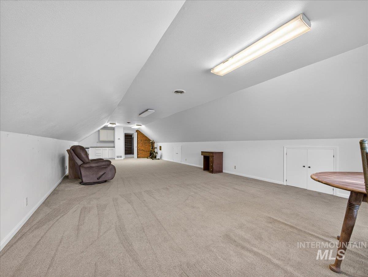Bonus room with lofted ceiling and light carpet