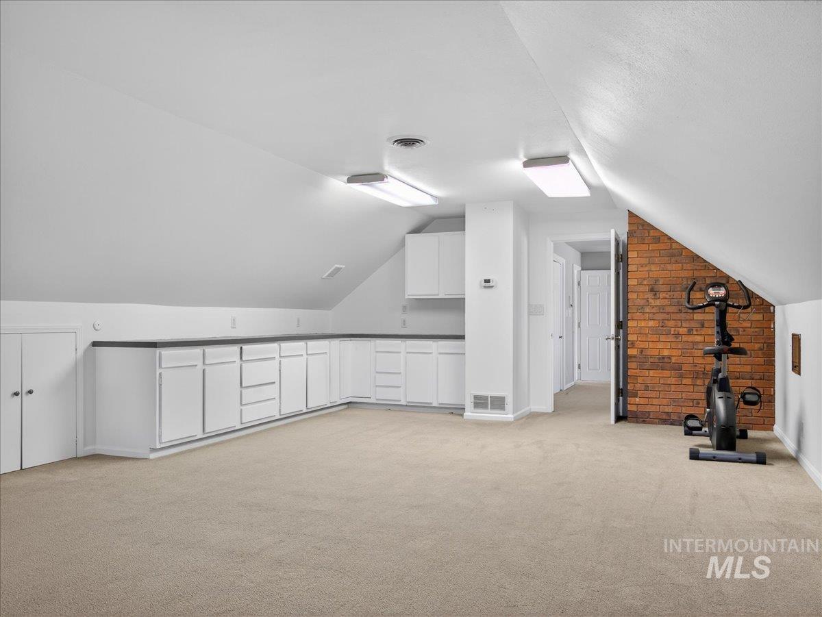 Additional living space with light carpet and vaulted ceiling