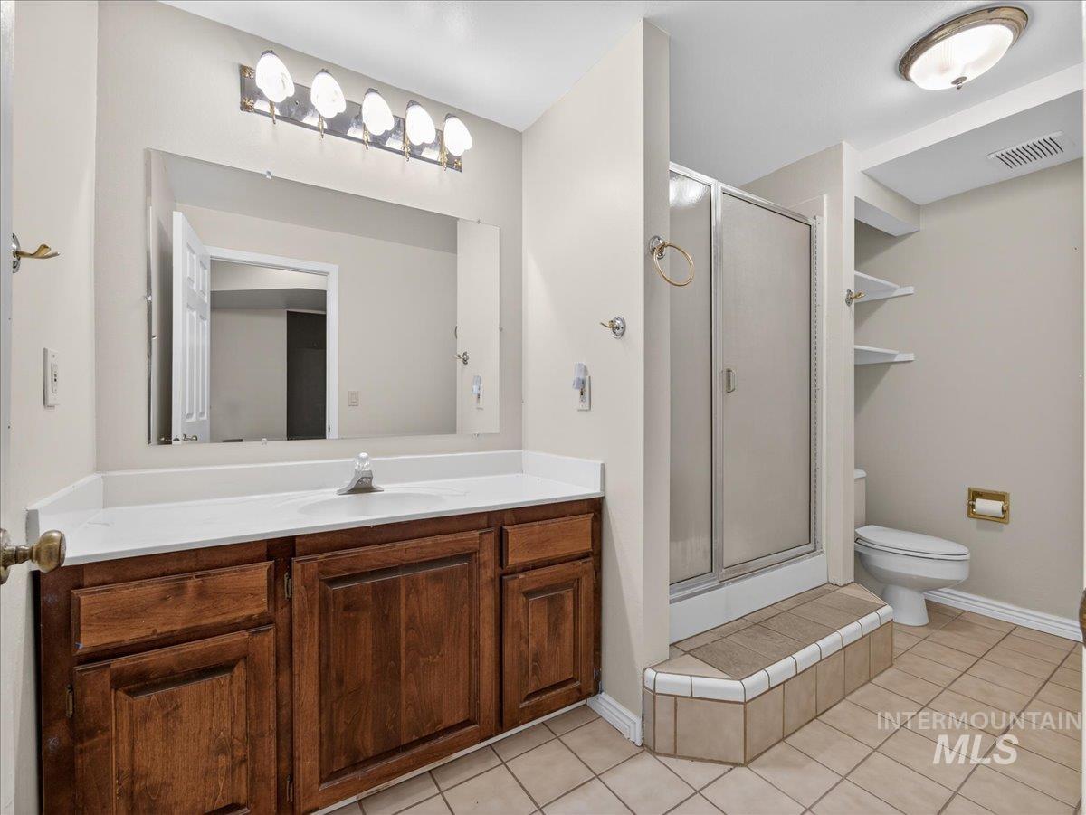 Full bathroom featuring vanity, a stall shower, and light tile patterned floors