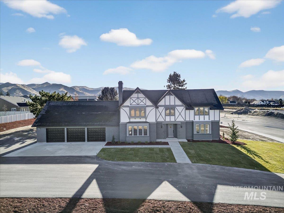 Tudor home featuring a mountain view, a front lawn, concrete driveway, and stucco siding