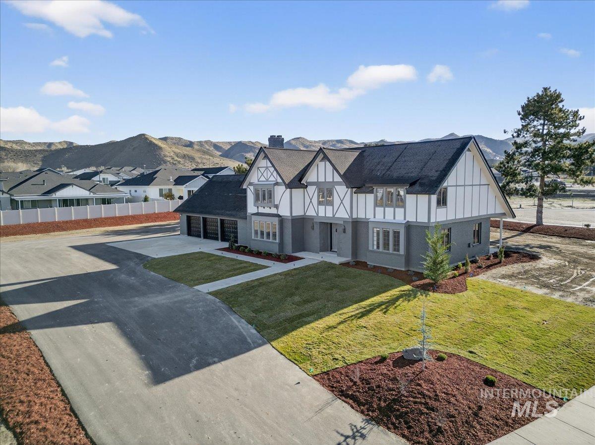 Tudor-style house with driveway, a chimney, a garage, and a mountain view