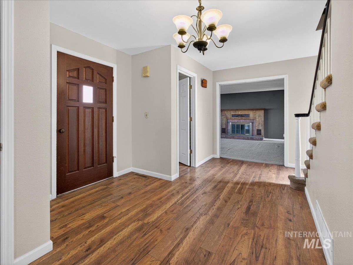 Entrance foyer with a fireplace, dark wood-style floors, a chandelier, and stairs
