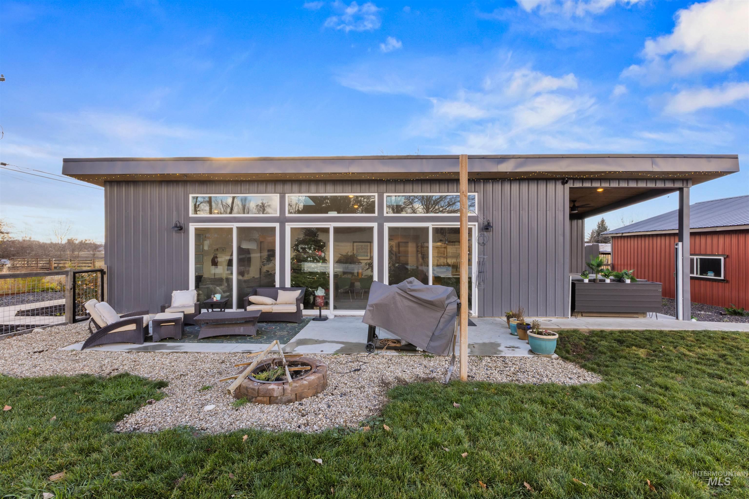 Back of house with a patio area and an outdoor living space with a fire pit