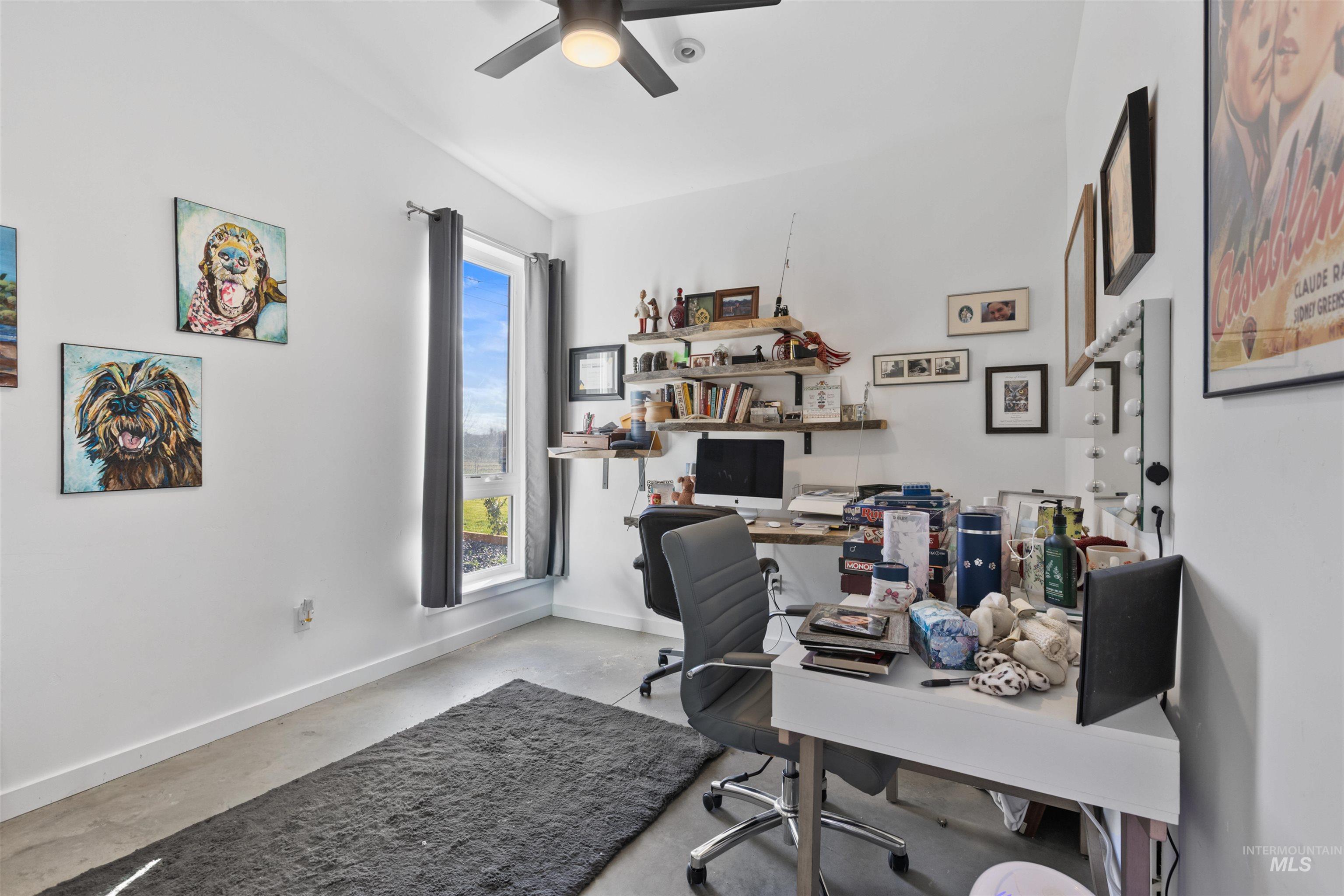 Office area featuring concrete floors and a ceiling fan