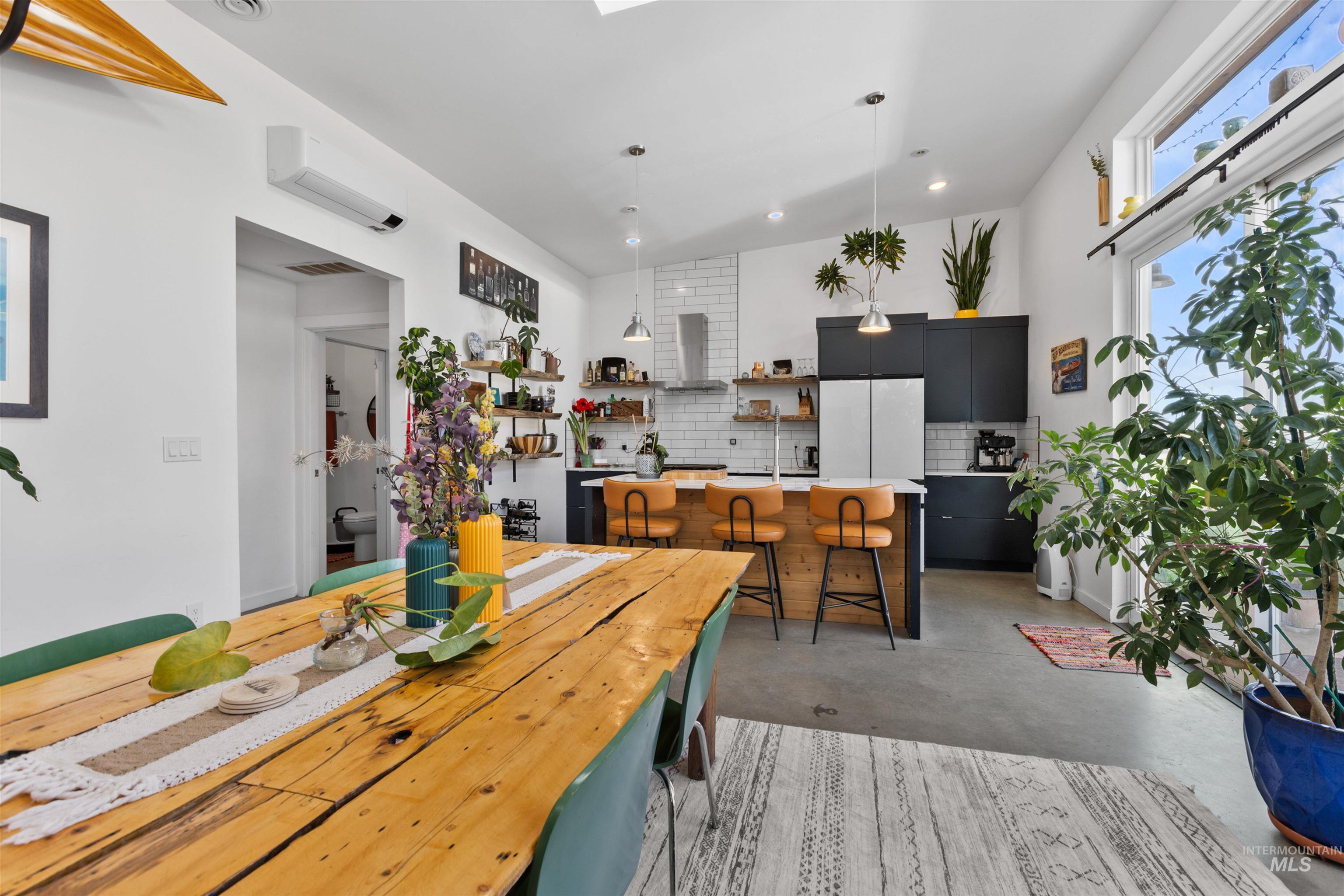 Dining area with concrete flooring, lofted ceiling, recessed lighting, and a wall mounted AC