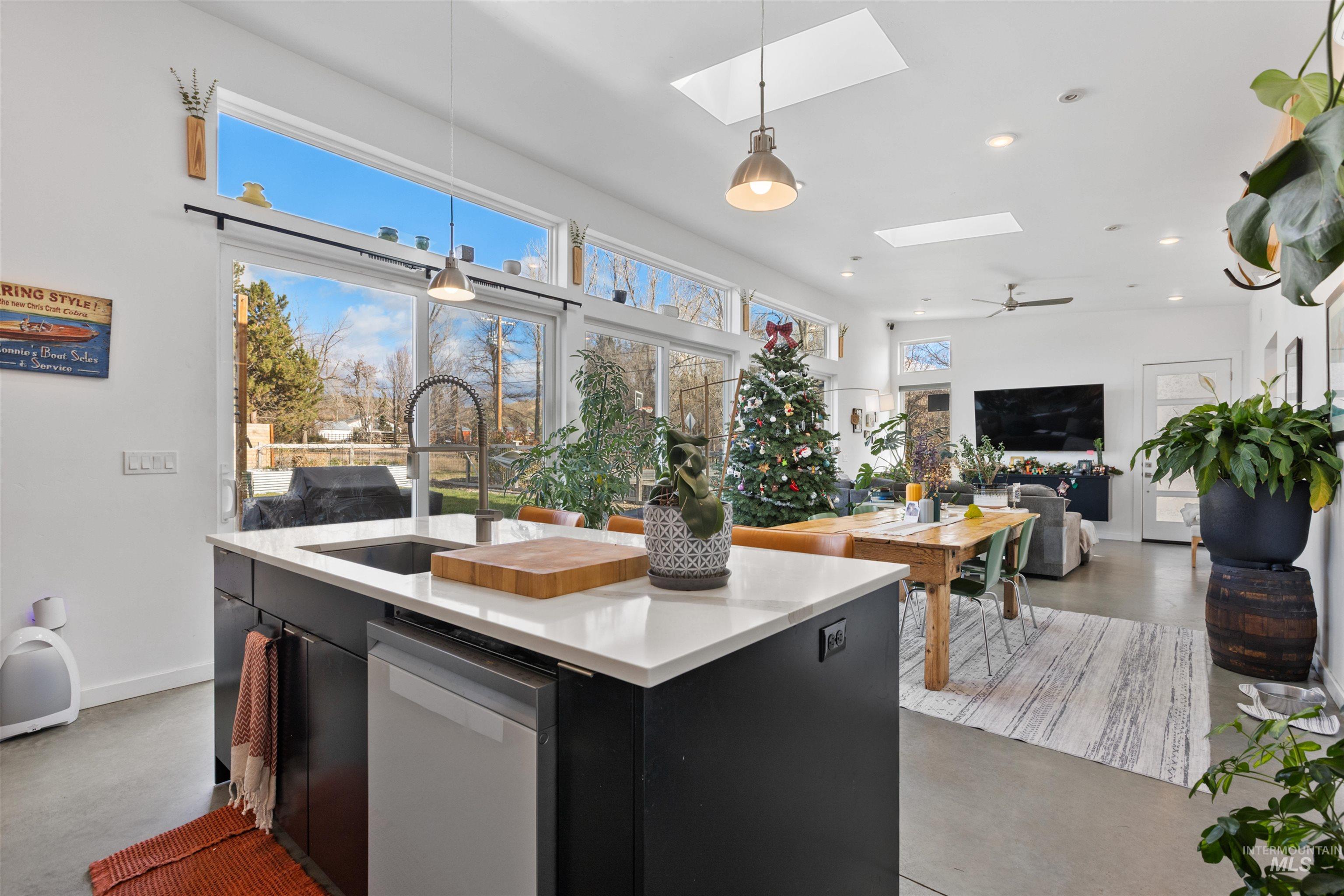 Kitchen featuring dark cabinets, hanging light fixtures, dishwasher, finished concrete flooring, and recessed lighting