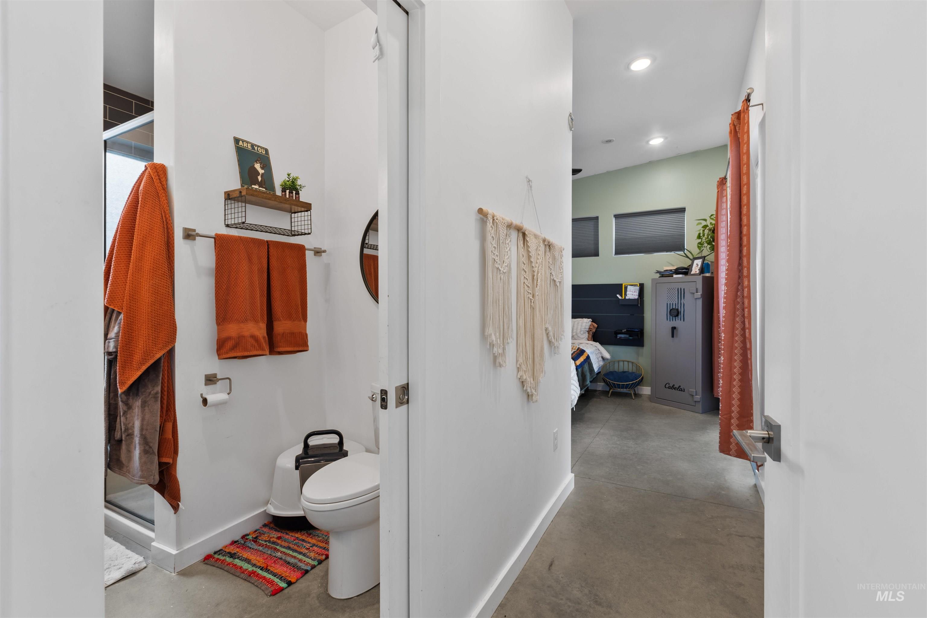 Bathroom featuring a stall shower, connected bathroom, concrete flooring, and recessed lighting