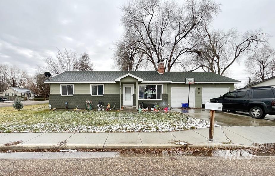 Single story home with driveway, brick siding, an attached garage, a chimney, and a shingled roof