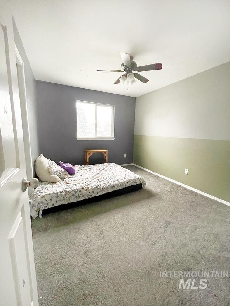 Carpeted bedroom featuring a ceiling fan and baseboards