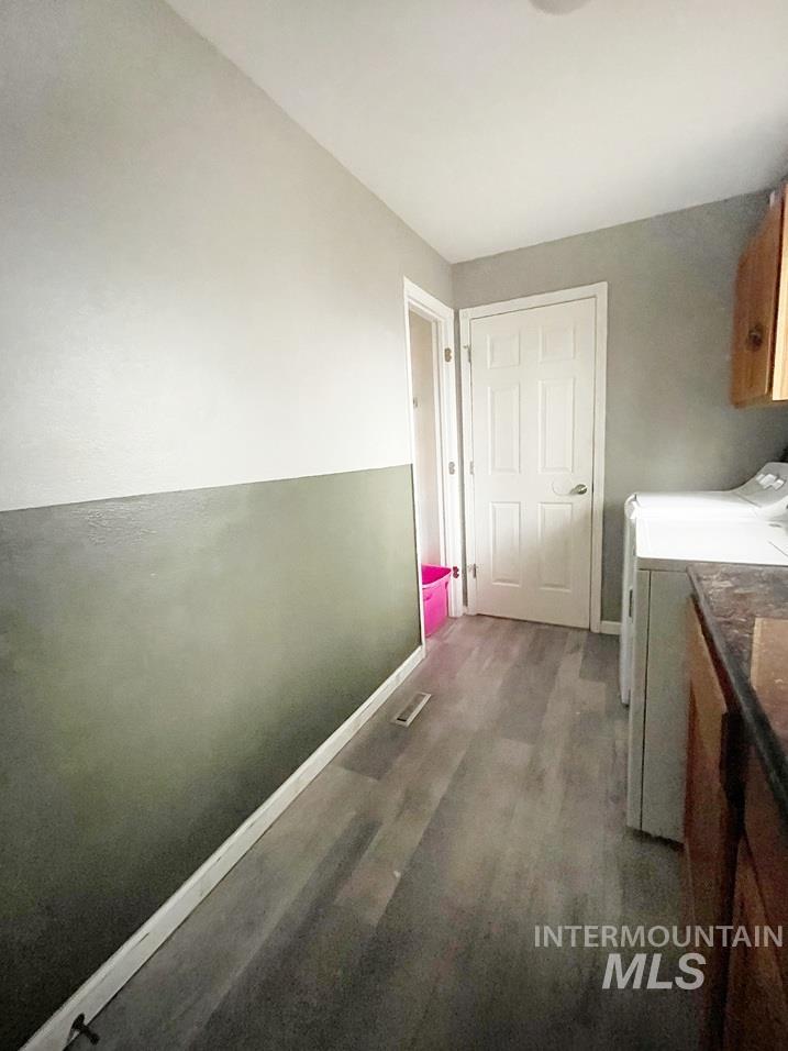 Washroom featuring cabinet space, washer and clothes dryer, and dark wood finished floors