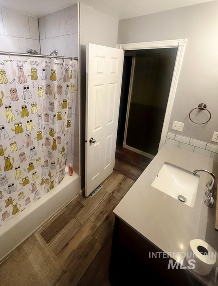 Bathroom with vanity, shower / bath combo, and wood finish floors