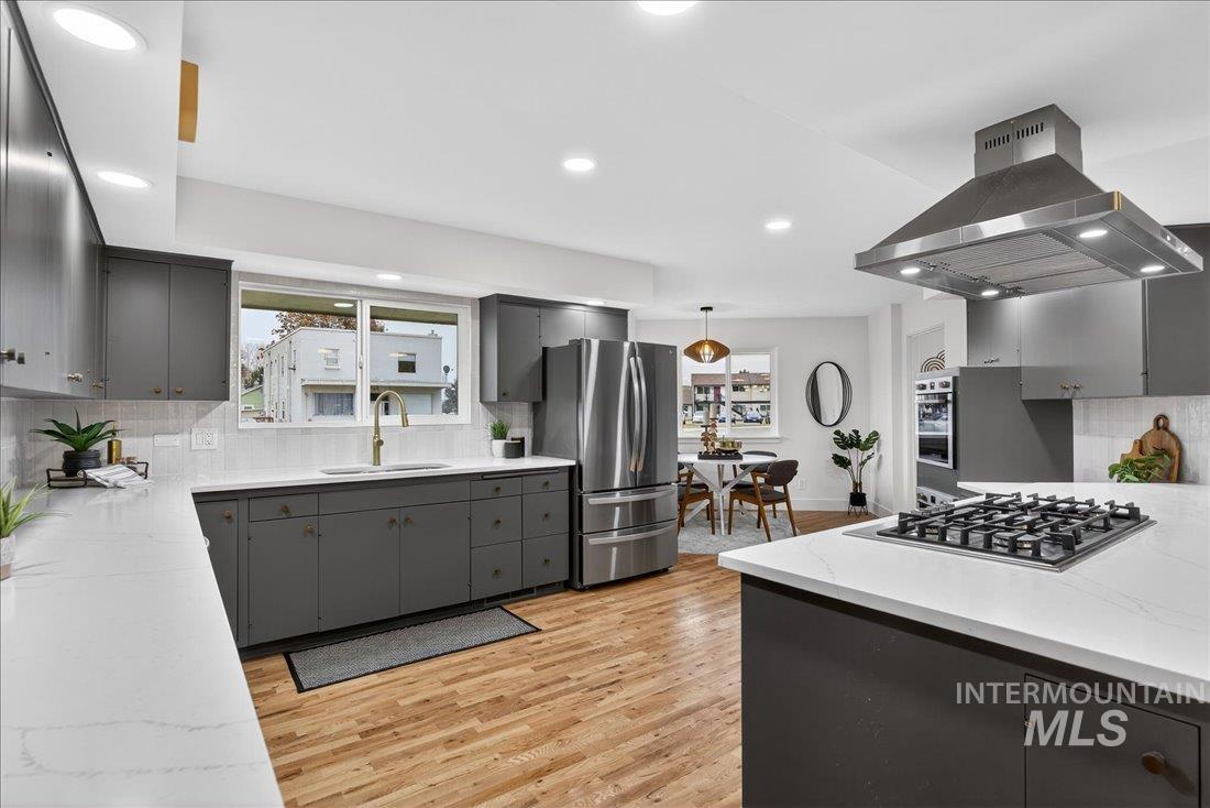 Kitchen featuring decorative backsplash, gray cabinetry, island range hood, appliances with stainless steel finishes, and recessed lighting