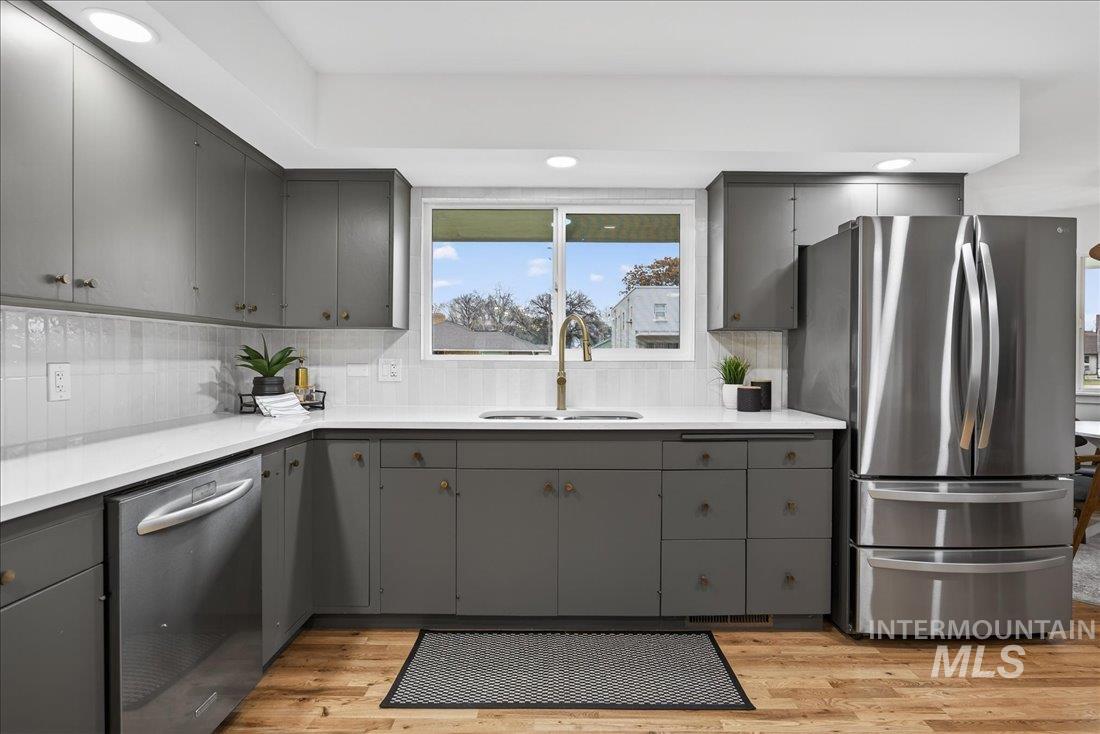 Kitchen featuring gray cabinets, stainless steel appliances, light wood-type flooring, recessed lighting, and tasteful backsplash