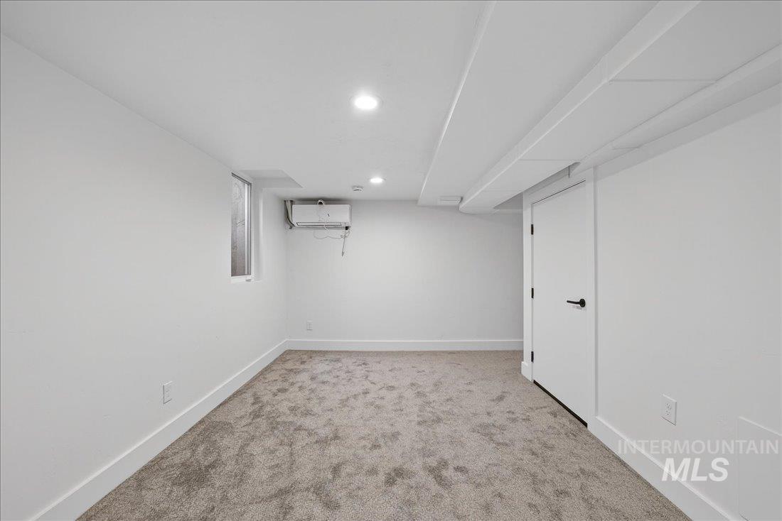 Basement with light colored carpet, recessed lighting, and an AC wall unit