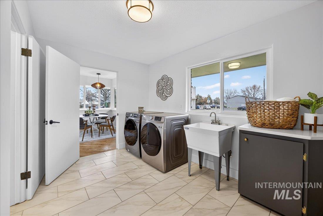 Laundry area featuring independent washer and dryer and light marble finish floors