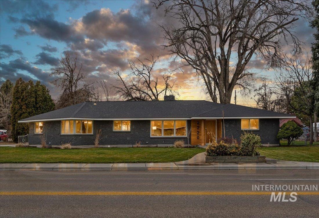 Ranch-style home featuring a front yard, a chimney, and brick siding