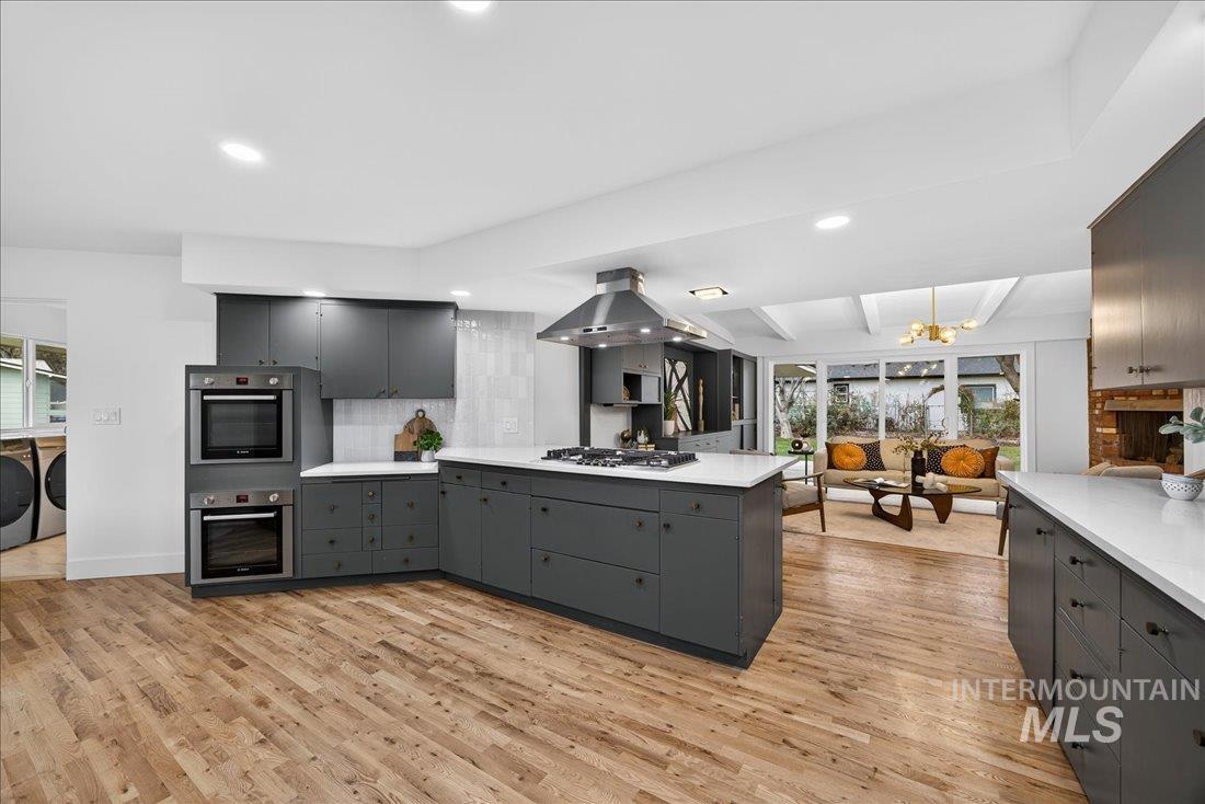 Kitchen with a peninsula, independent washer and dryer, gray cabinetry, light wood finished floors, and recessed lighting