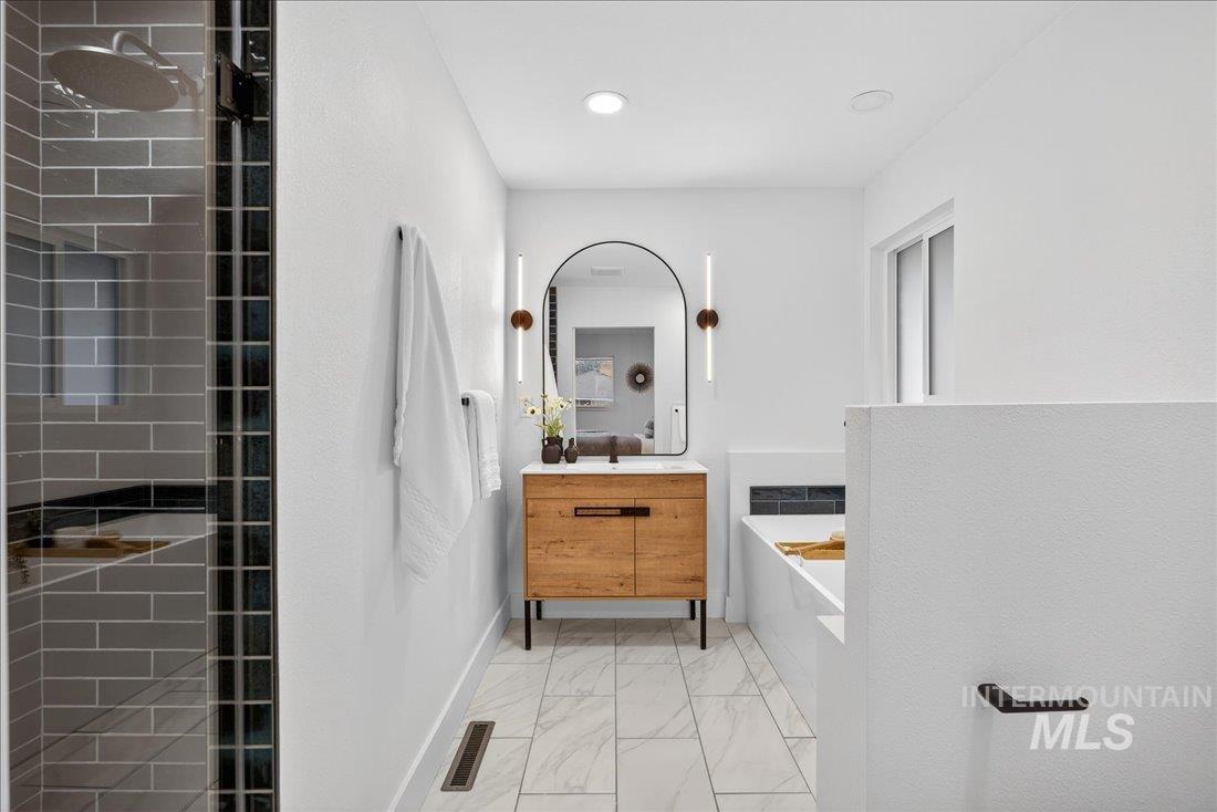 Full bathroom featuring vanity, a garden tub, light marble finish flooring, and a shower stall