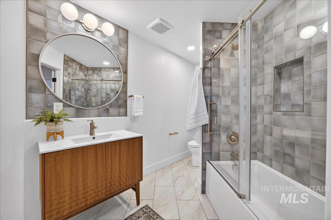 Full bathroom with tiled shower / bath, vanity, and light marble finish flooring