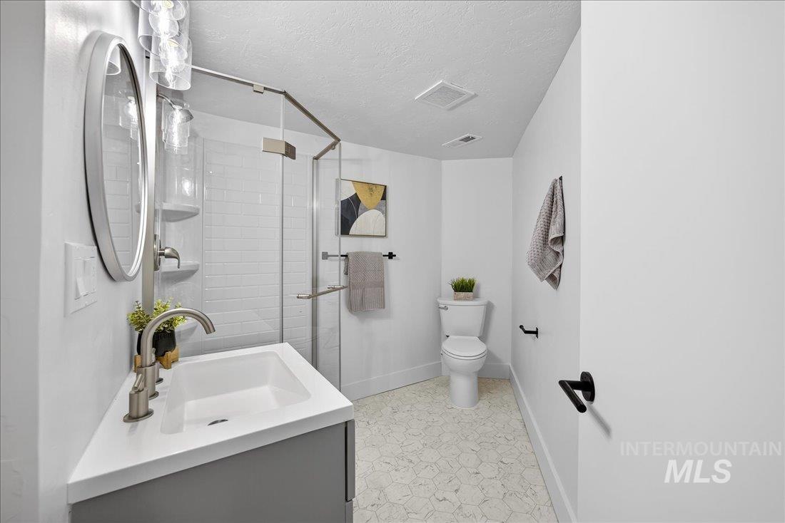 Full bath with a stall shower, vanity, and a textured ceiling