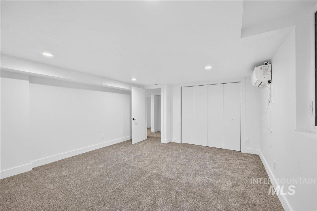 Unfurnished bedroom featuring carpet floors, a wall unit AC, a closet, and recessed lighting