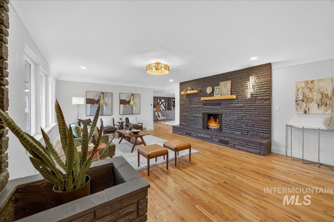 Living area with a stone fireplace, light wood-type flooring, and recessed lighting