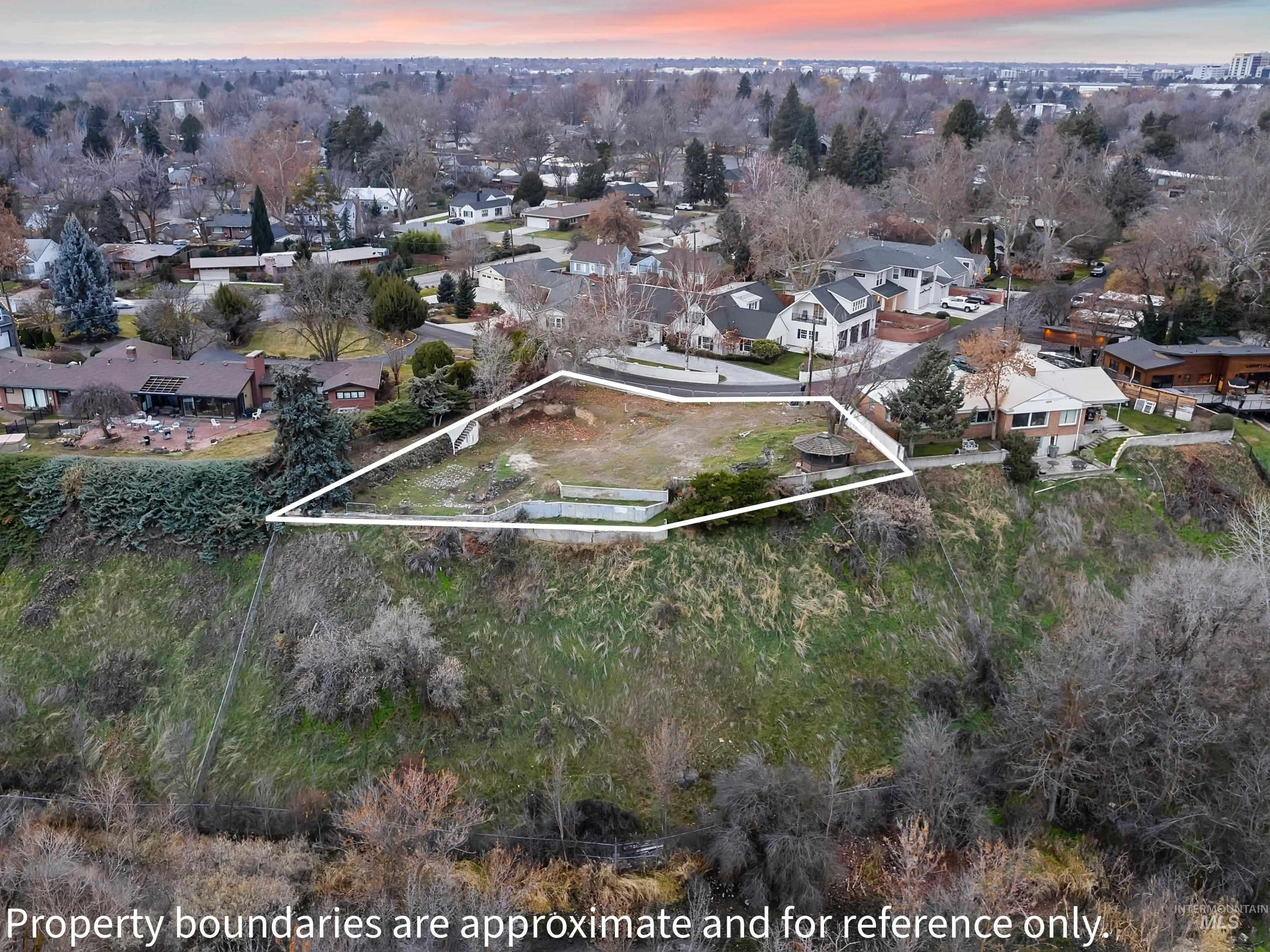 Aerial view of residential area with property parcel outlined and a tree filled landscape