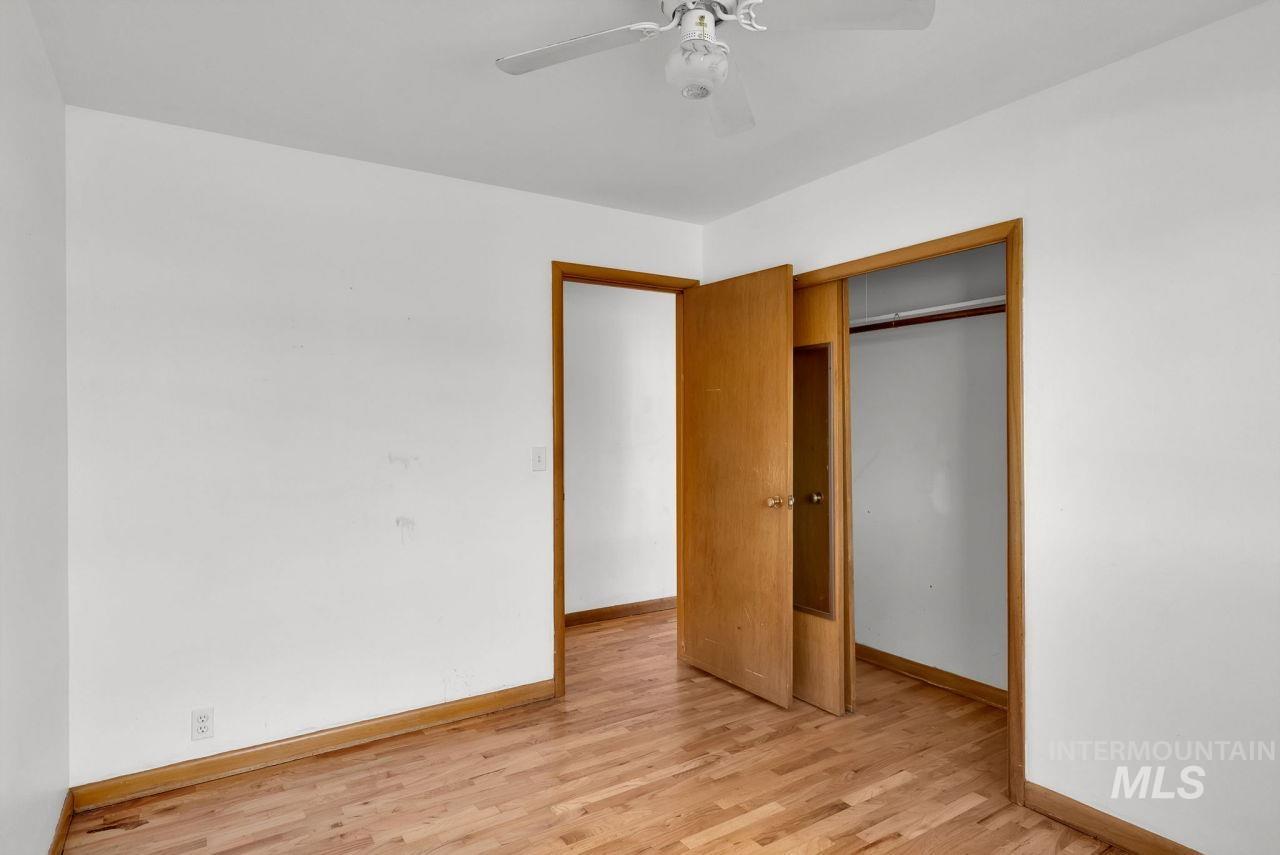 Unfurnished bedroom with light wood finished floors, ceiling fan, and a closet