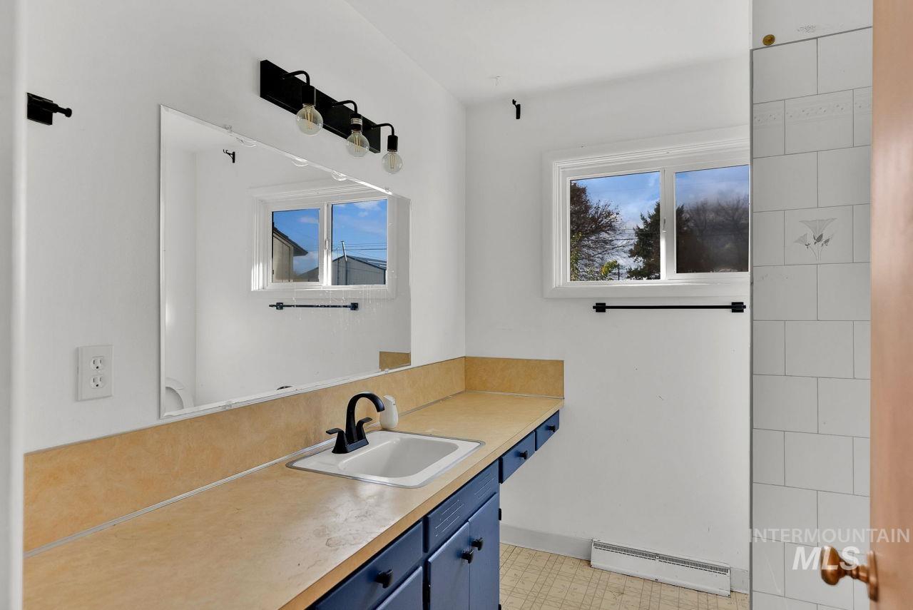 Bathroom featuring a baseboard heating unit, light floors, and vanity